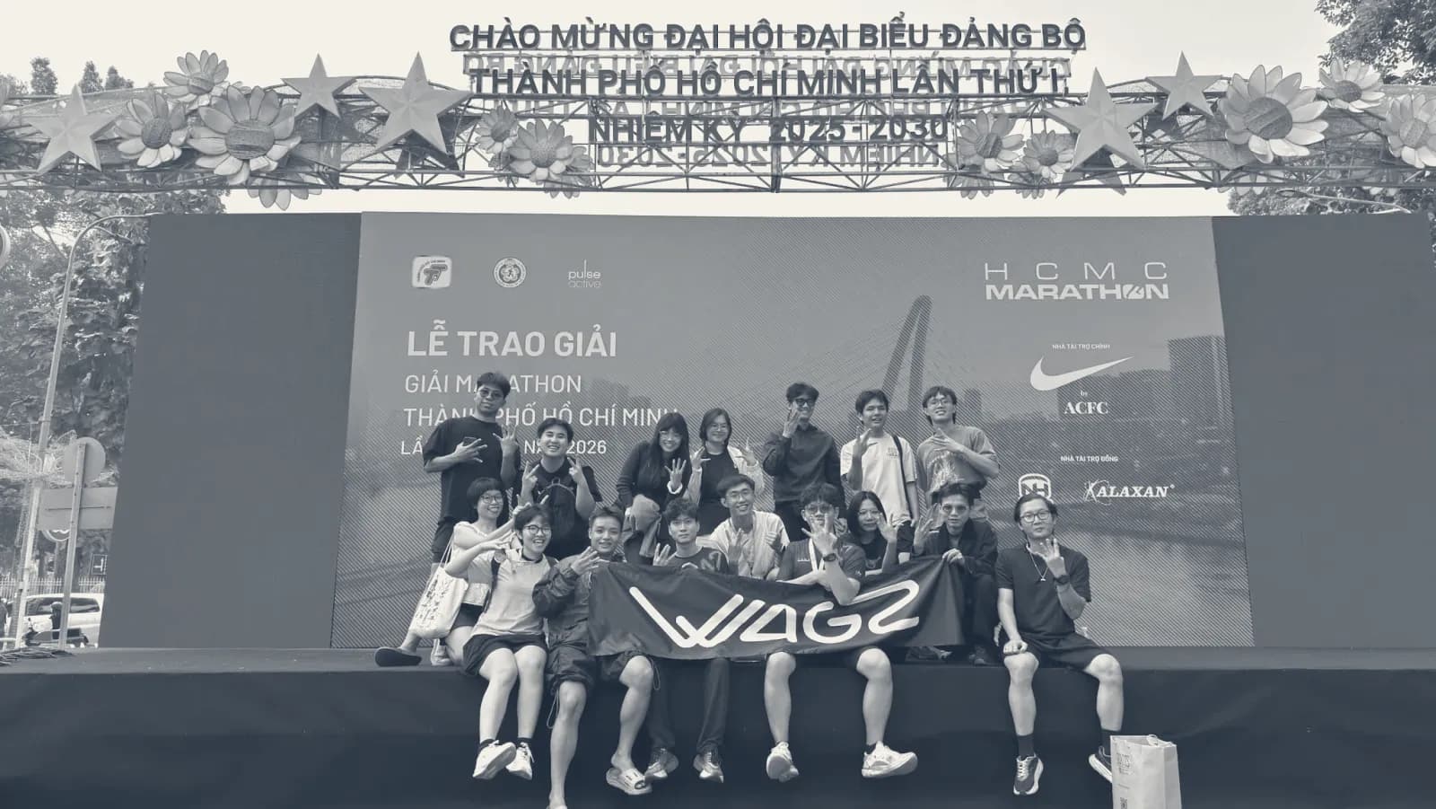 Một nhóm W chụp ảnh chung trước sân khấu trao giải của một giải marathon.