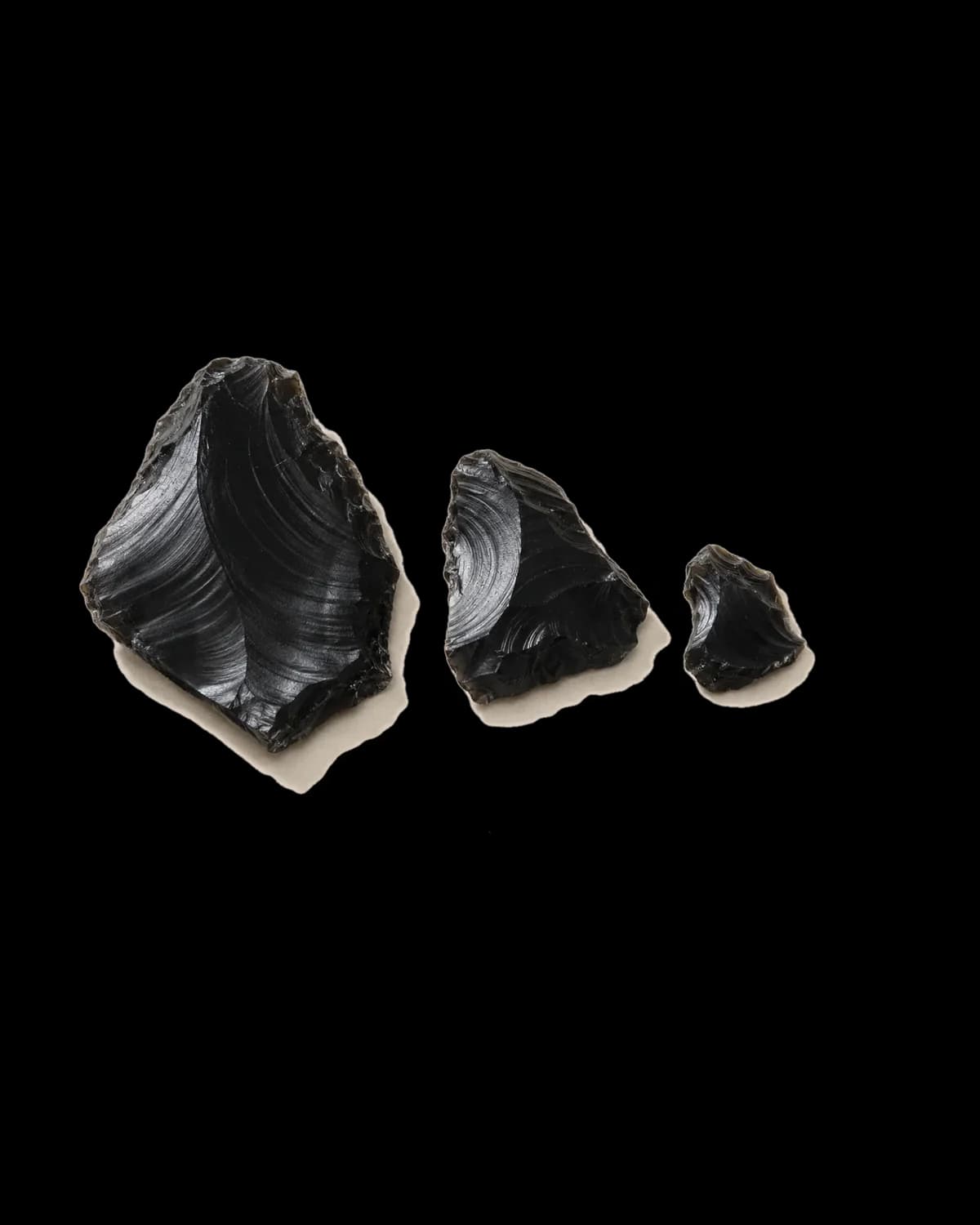 Một khối đá đen tách thành ba mảnh vỡ rời nhau, đặt trên giấy.